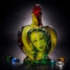 Cor Vitae heart-shaped glass bottle with inner face, red stopper, and golden-green tones
