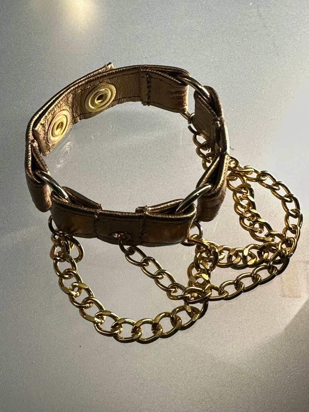 Metallic copper leather bracelet with gold hardware and draped chains